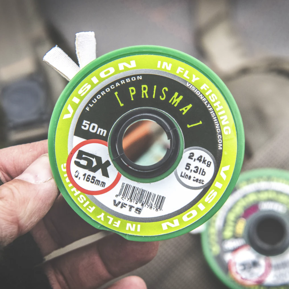 Vision Prisma FL Carbon Tippet Spule 4X, Vision Prisma FL Carbon Tippet 5X Fluorocarbon, Vision Prisma FL Carbon Tippet 6X feines Vorfachmaterial, Vision Prisma FL Carbon Tippet 7X für heikle Forellen, Detailaufsicht Prisma FL Carbon Tippet Beschriftung, Nahaufnahme Fluorocarbon Vorfach Vision Prisma, Prisma FL Carbon Tippet Spulen farbcodiert verbunden, Fliegenfischer nutzt Vision Prisma FL Carbon Tippet am Bergbach